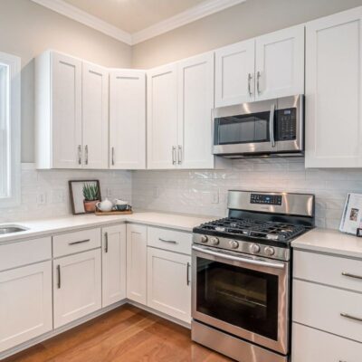 White kitchen cabinets. Stainless steel appliance,s including an oven with overhead microwave.