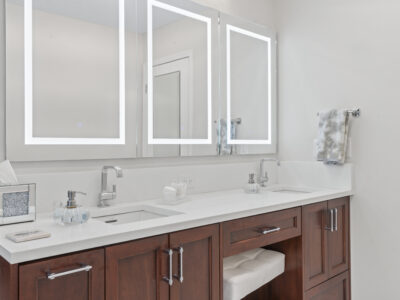 03-DSC04370 Modern bathroom vanity with dual sinks, sleek white countertop, contemporary mirrors, and wooden cabinetry, showcasing a stylish and functional design for remodeling projects.