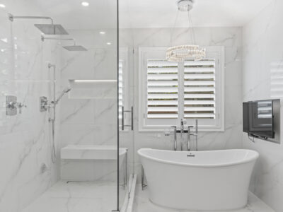 08-DSC04321 Modern bathroom with a freestanding bathtub, glass shower enclosure, marble walls, and a sleek chandelier, showcasing a luxurious design ideal for remodeling projects.