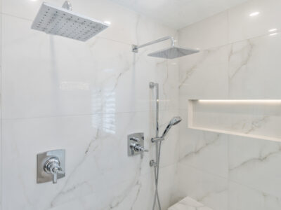 16-DSC04307 Modern bathroom shower with dual showerheads, sleek chrome fixtures, and elegant marble wall tiles, showcasing a stylish and functional design for remodeling projects.
