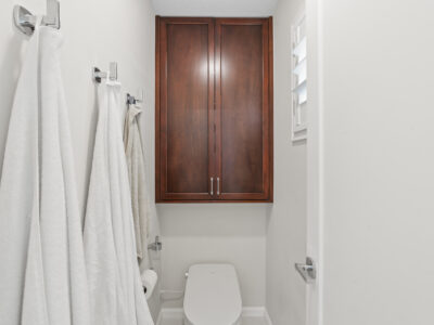 18-DSC04282 Bathroom with wooden cabinetry, white towels hanging, and modern toilet, showcasing a clean and functional design for remodeling inspiration.