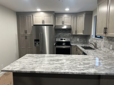 20-Nov 19 2024 12_01am-M4iA Modern kitchen featuring sleek gray granite countertops, stainless steel appliances, and light wood cabinetry, illustrating a stylish and functional space for remodeling decisions.