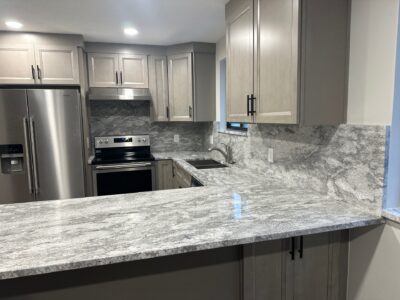 21-Nov 19 2024 12_01am-4zeN Modern kitchen featuring gray granite countertops, light wood cabinetry, stainless steel appliances, and a spacious layout, ideal for remodeling discussions.