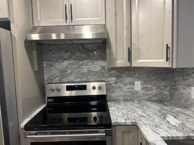 24-Nov 19 2024 12_01am-kVL8 Modern kitchen featuring sleek gray granite countertops, stainless steel appliances, and light wood cabinetry, illustrating a stylish and functional remodel.