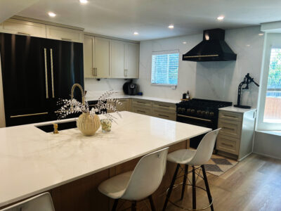 Alyssa1 Modern kitchen featuring a large white countertop, black cabinetry, and stainless steel appliances, highlighting design elements for kitchen remodeling and countertop material selection.