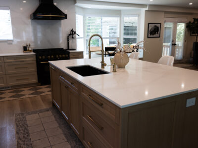 Alyssa7 Modern kitchen featuring a light-colored quartz countertop, wooden cabinetry, a black range, and stylish decor elements, illustrating a contemporary design suitable for remodeling projects.