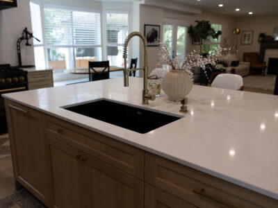 Alyssa8 Modern kitchen island with white quartz countertop, integrated black sink, stylish faucet, and decorative vase, showcasing ideal design elements for kitchen remodeling.