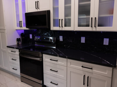 Chris11 Modern kitchen featuring sleek black countertop, stainless steel appliances, and white cabinetry with glass accents, ideal for countertop material comparison in remodeling projects.