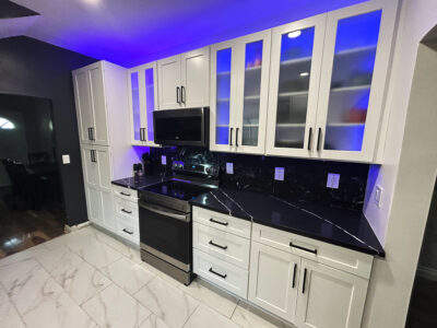 Chris5 Modern kitchen featuring sleek white cabinetry, black countertop, stainless steel appliances, and blue LED lighting accents.