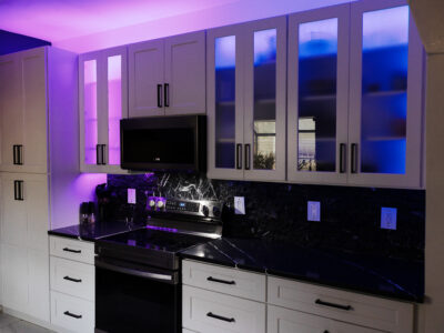 Chris6 Modern kitchen featuring sleek black countertops, stylish cabinetry with illuminated glass doors, and stainless steel appliances, showcasing a contemporary design ideal for remodeling projects.