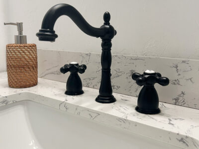 Kristen2 Black faucet and handles on a marble countertop with a soap dispenser, highlighting modern bathroom design elements for remodeling.