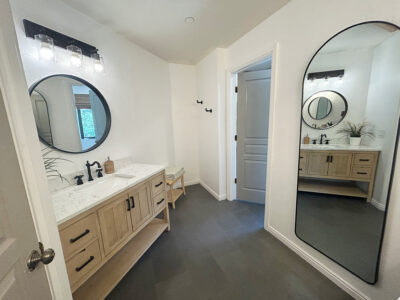 Kristen4 Modern bathroom interior featuring a stylish vanity with marble countertop, dual circular mirrors, and contemporary lighting, emphasizing design and functionality in home remodeling.