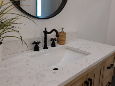 Kristen6 Bathroom countertop with white marble surface, black faucet and handles, sink, and decorative elements, reflecting modern design and functionality in home remodeling.