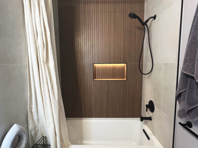Natale3 Modern bathroom featuring a freestanding tub, textured wood panel accent wall, and sleek black shower fixtures, emphasizing contemporary design and remodeling potential.