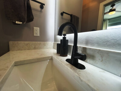 Natale4 Bathroom countertop featuring a sleek black faucet, stylish soap dispenser, and modern mirror, illustrating elegant design choices for bathroom remodeling.
