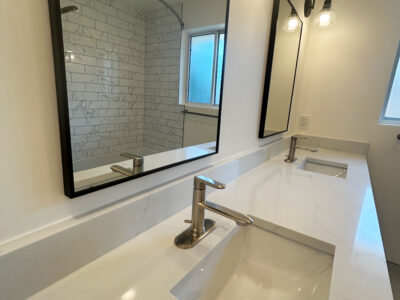 Zack4 Modern bathroom countertop with dual sinks, sleek faucet, and large mirrors reflecting a bright, minimalist design.