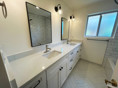 Zack5 Modern bathroom with dual sinks, white cabinetry, large mirrors, and natural light from window, showcasing sleek countertop design ideal for remodeling projects.