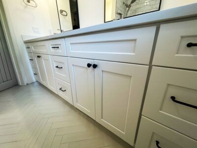 Zack7 White bathroom cabinetry with black hardware and a sleek countertop, showcasing modern design elements for remodeling projects.